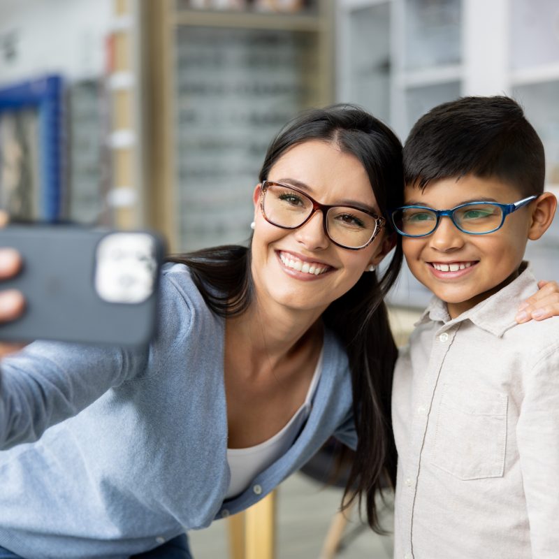 A mother and son pose together for a selfie in their new prescription glasses.